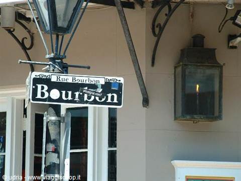 Rue Bourbon street sign on iron pole with black lantern on the wall