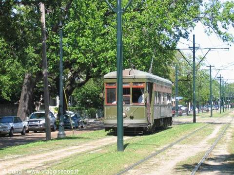 Green vintage streetcar on grassy tracks along St. Charles, New Orleans