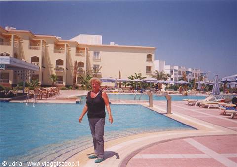Woman standing by the hotel pool, sun loungers and umbrellas in the sun