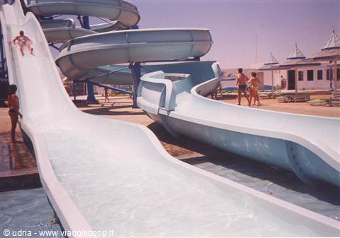 Child sliding down white water slide, blue slides and kids in the sun