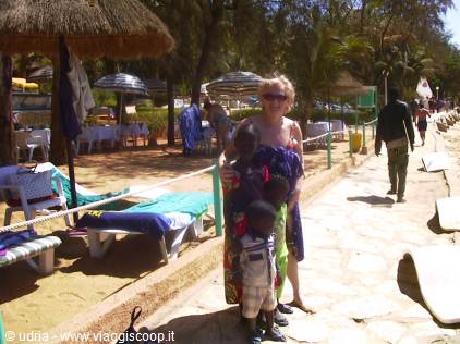 Woman with two children walking along the beach past sun loungers and straw umbrellas