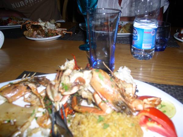 Wooden table with crabs and lobsters on plates, blue glass, water