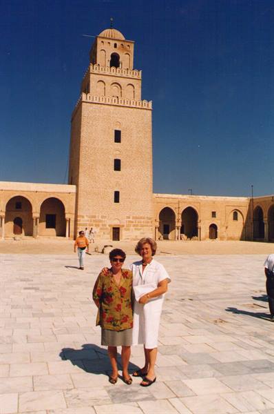 Two women posing in front of the minaret of the Great Mosque of Kairouan