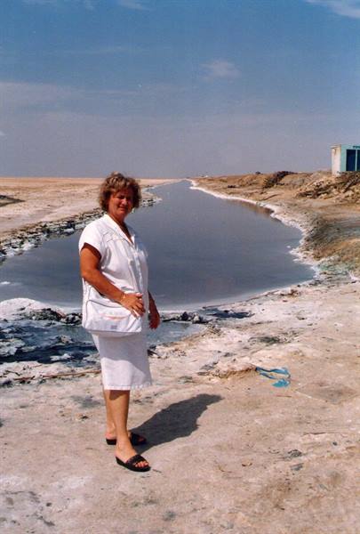 Woman in white beside a salty pool on salt-crusted ground