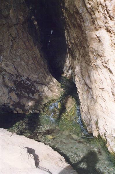 Clear stream flowing between limestone rock walls in a dark gorge