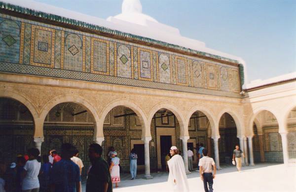 Tourists walking in the arcade courtyard of the Great Mosque of Kairouan