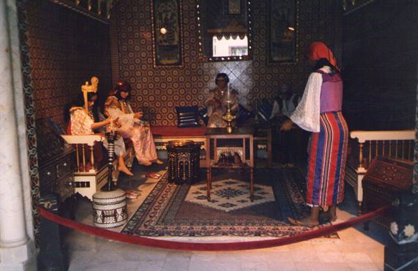 Costumed mannequins in traditional interior with carpets and couches, museum