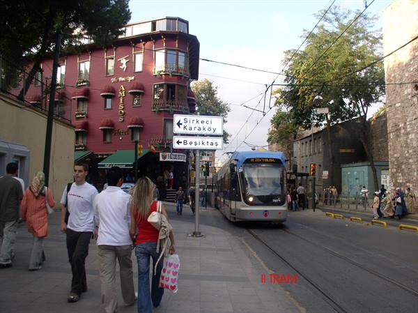 Tram on Sithane Tepe in Istanbul, pedestrians walking past red building