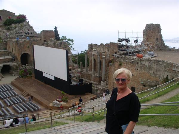 Blonde woman in sunglasses at Taormina's ancient Greek theatre, ruins and stage screen
