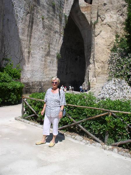 Woman in front of the Orecchio di Dionisio, Syracuse, sunlight on limestone rock