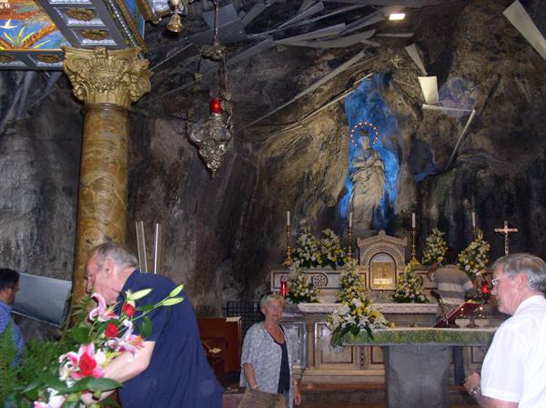 Worshippers with flowers inside Saint Rosalia's cave on Mount Pellegrino, illuminated statue