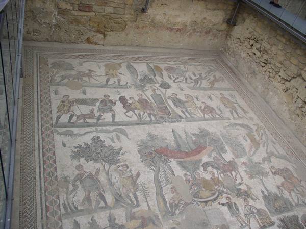 Roman mosaic with hunting scenes and figures, protected by glass at the archaeological site