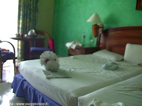 Hotel room with double bed, towel swan decoration, green walls and lamp