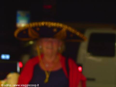 Tourist in gold sombrero and red shawl at night, blurred photo