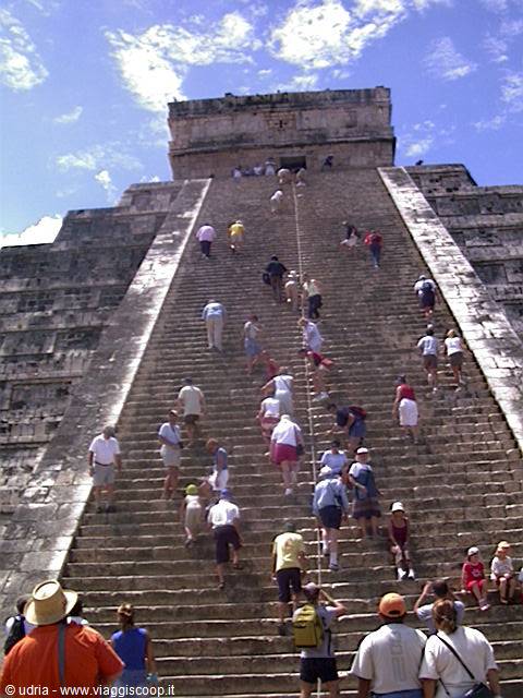Tourists climb the steep stone staircase of the Chichén Itzá pyramid