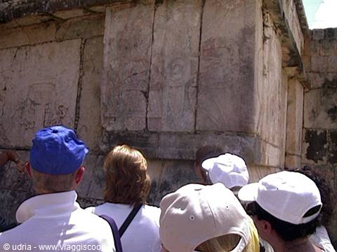 Tourists in caps admire stone Maya carvings at Chichén Itzá