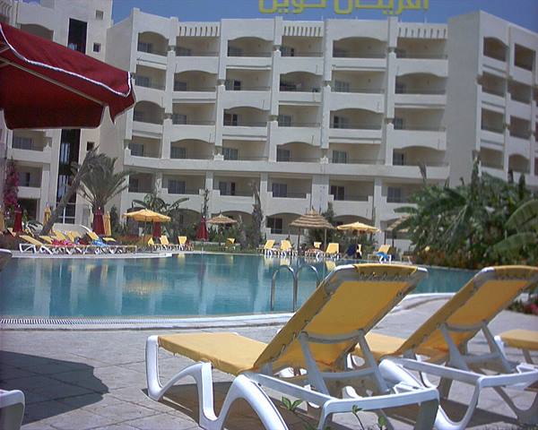 Yellow loungers by a large hotel pool with palms and parasols
