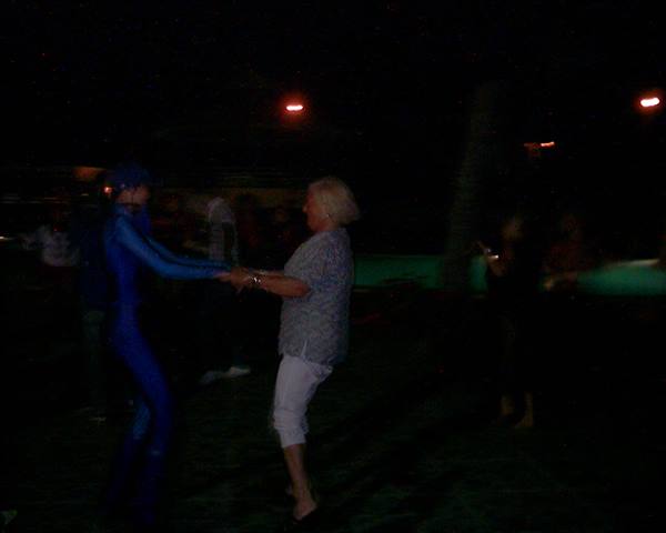 Two people dance at night at a dimly lit outdoor party