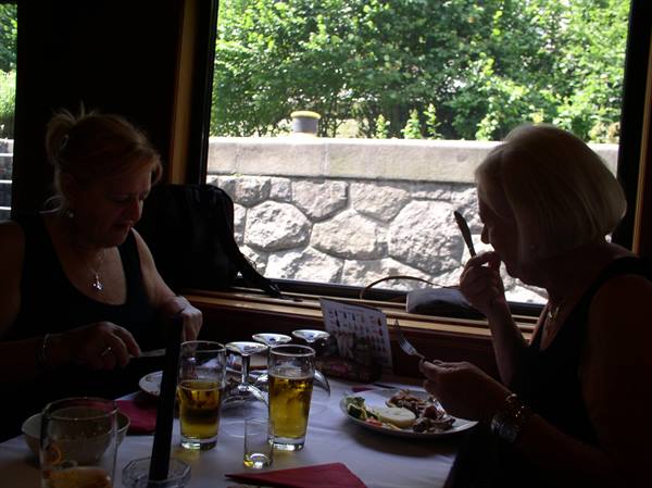 Two women eating and drinking beer at a bright table