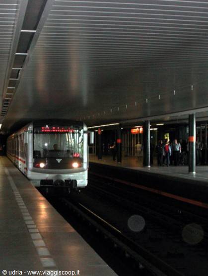 Subway train arriving on the track, passengers waiting on the lit platform