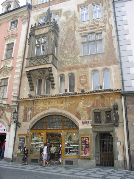 Tourists outside the painted Storch House in Prague, with shop signs