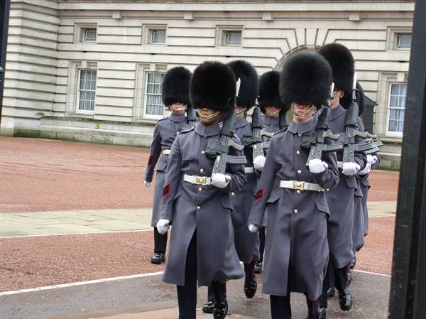 Guards in bearskin caps march with rifles at Buckingham Palace