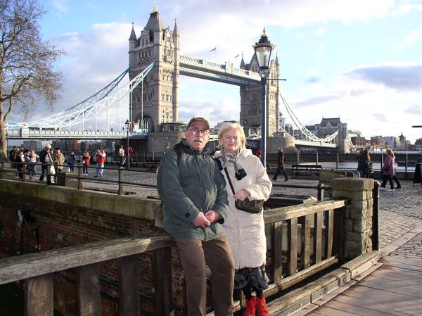 Couple leaning on a wooden fence in front of Tower Bridge, London