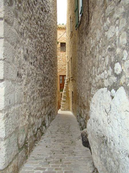 Narrow alley between stone walls and cobblestones, natural daylight