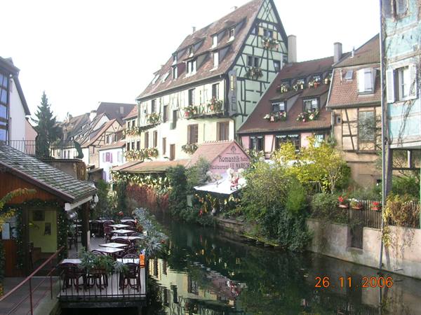 Timbered houses line the canal, restaurant tables by the water, Colmar