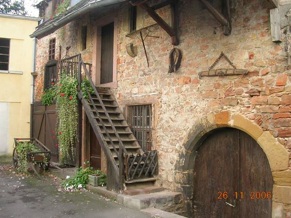 Stone farmhouse courtyard with wooden staircase and arched wooden door
