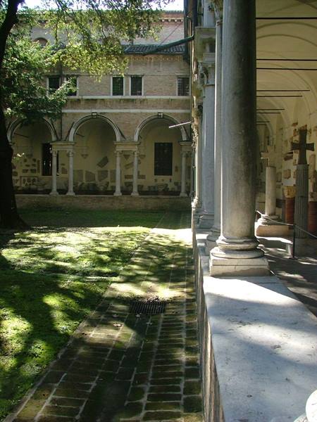 Cloister with marble columns, grassy courtyard and sunlit arches
