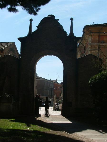 Backlit brick gate, people sitting in the shade of the arch