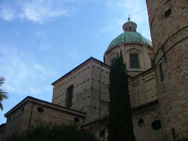 green copper dome over ancient bricks, cypress tree against blue sky