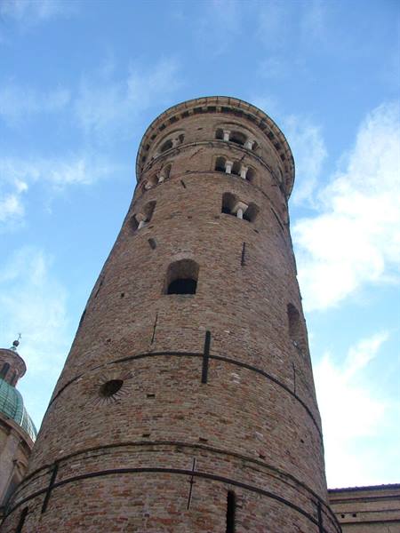 medieval brick tower with arched windows seen from below against blue sky
