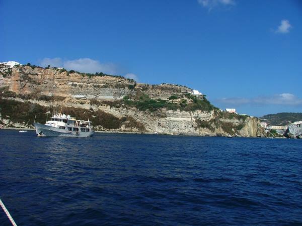White motor yacht in front of Ponza's tuff cliffs