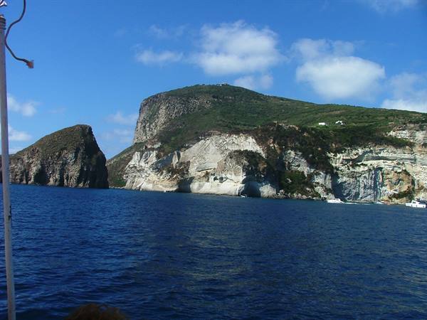 Sea stack and white cliffs of Ponza seen from a boat under blue sky