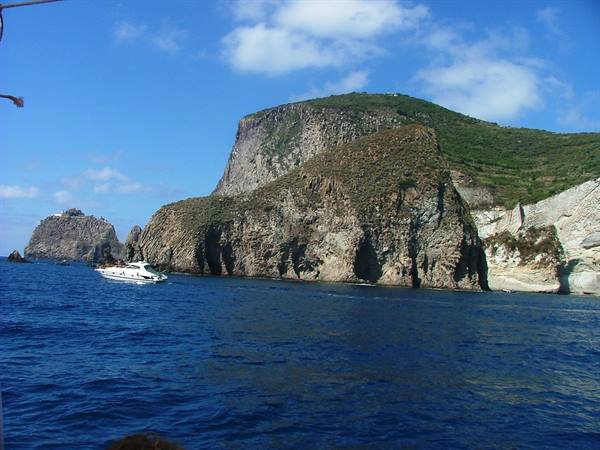 Motorboat sailing past Ponza's rugged cliffs and green hills