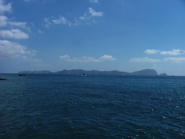 Blue sea with mountainous islands on the horizon under cloudy sky