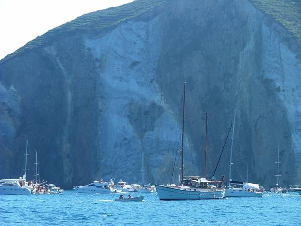 Sailboats and motor yachts anchored beneath tall rock cliffs at Ponza