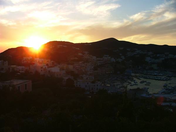 Sun setting behind hills above Ponza harbor and its boats