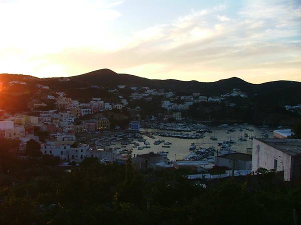 Ponza harbor with moored boats among colorful houses and hills at dusk