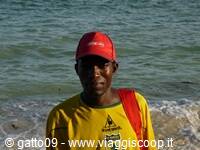 Lifeguard in red cap and yellow shirt standing by the waves on the beach