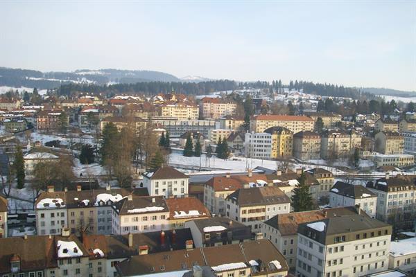 Snowy rooftops and colorful buildings among the hills of St. Gallen