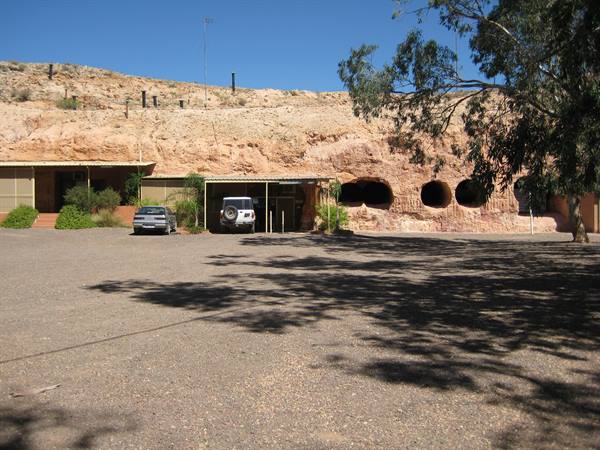 Dwellings carved into sandstone rock with parked cars, Coober Pedy