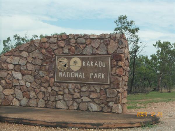 Stone entrance sign of Kakadu National Park, trees and cloudy sky