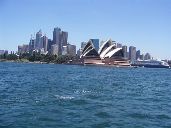 Sydney Opera House with white sails, skyscrapers and a cruise ship in the harbour