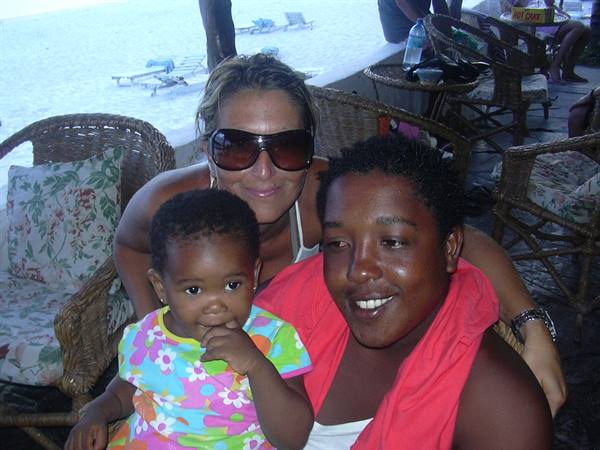 Woman in sunglasses hugging two smiling children on wicker chairs