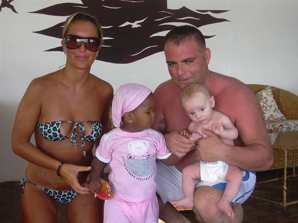 Couple in swimwear with two children, one in pink headscarf, indoors