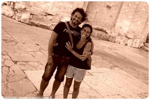 Smiling couple embracing on stone pavement in front of ancient ruins