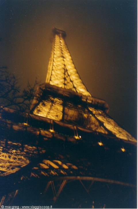 The Eiffel Tower lit up at night, golden iron against dark sky